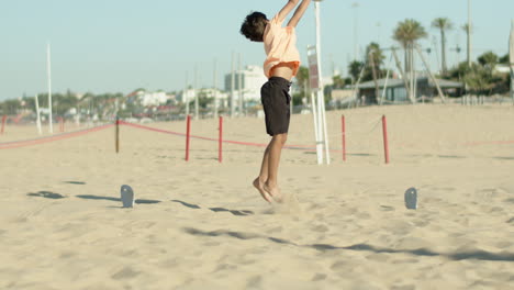 Vertical-motion-of-boy-keeping-goal-and-clearing-ball-on-beach